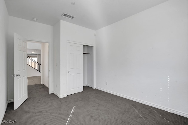 unfurnished bedroom with a closet and dark colored carpet