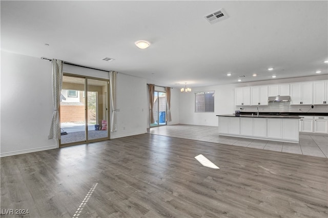 unfurnished living room with sink, a chandelier, and light hardwood / wood-style floors