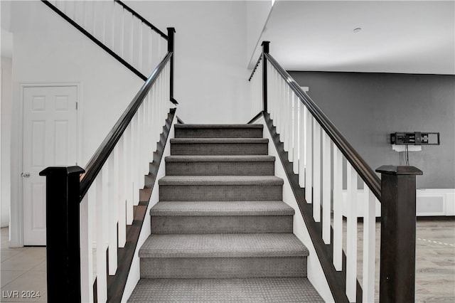 stairway featuring a towering ceiling and hardwood / wood-style floors