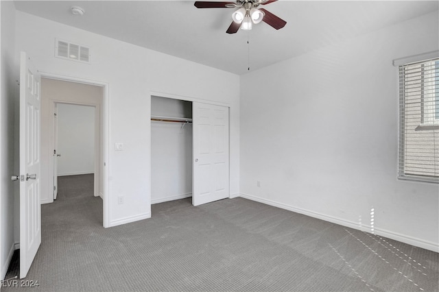 unfurnished bedroom with dark carpet, ceiling fan, and a closet