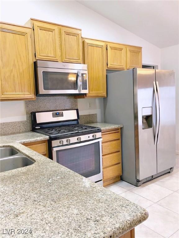 kitchen with light tile patterned floors, stainless steel appliances, and vaulted ceiling