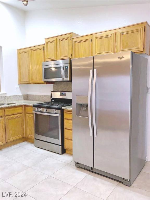 kitchen with light tile patterned flooring, stainless steel appliances, and high vaulted ceiling