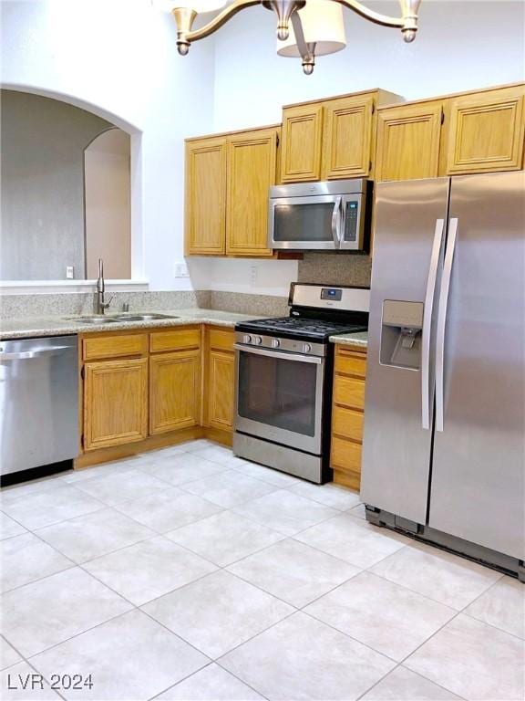 kitchen with sink, light tile patterned floors, stainless steel appliances, and an inviting chandelier