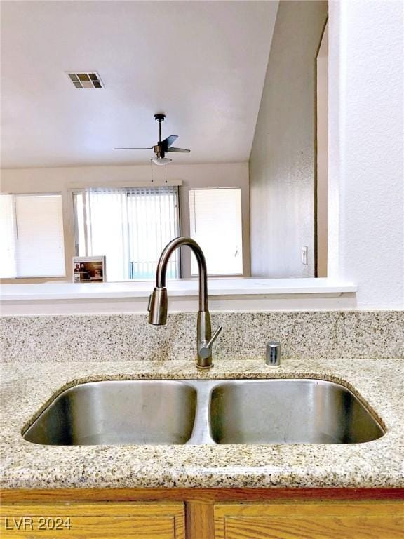 interior details with light stone countertops, sink, and ceiling fan