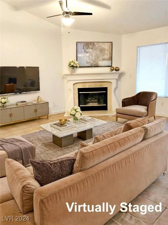 living room featuring ceiling fan, a premium fireplace, and light hardwood / wood-style flooring