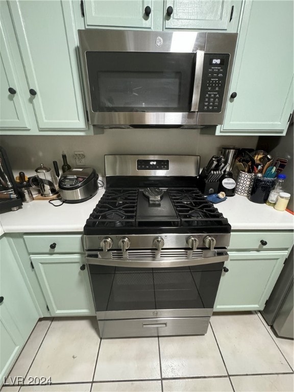 kitchen featuring green cabinetry, light tile patterned flooring, and appliances with stainless steel finishes