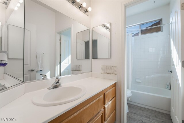 full bathroom with hardwood / wood-style floors, shower / tub combo with curtain, vanity, and toilet