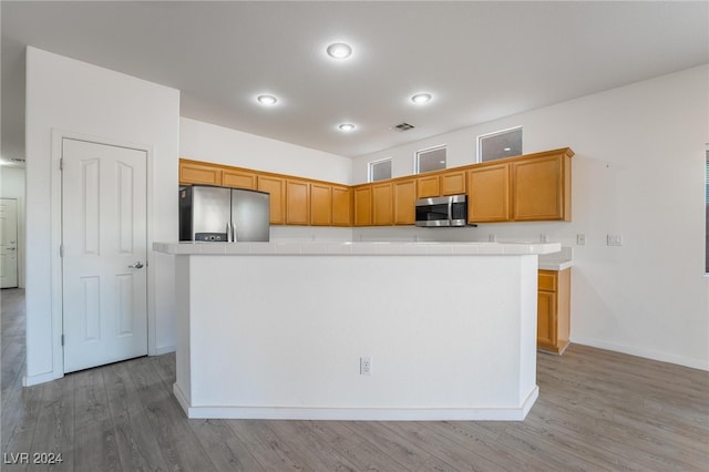 kitchen with appliances with stainless steel finishes, light wood-type flooring, and a center island