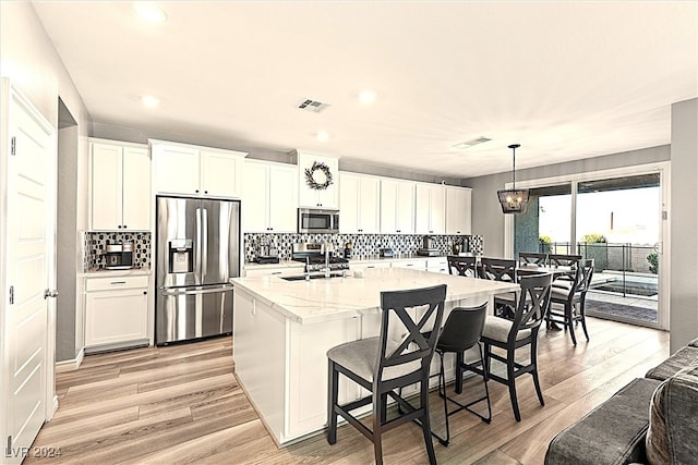 kitchen with appliances with stainless steel finishes, light hardwood / wood-style floors, and white cabinetry