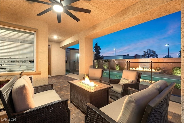 patio terrace at dusk featuring an outdoor living space with a fire pit and ceiling fan