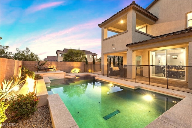 pool at dusk featuring a patio