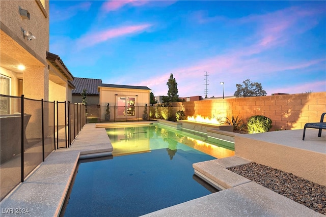 pool at dusk featuring a patio area