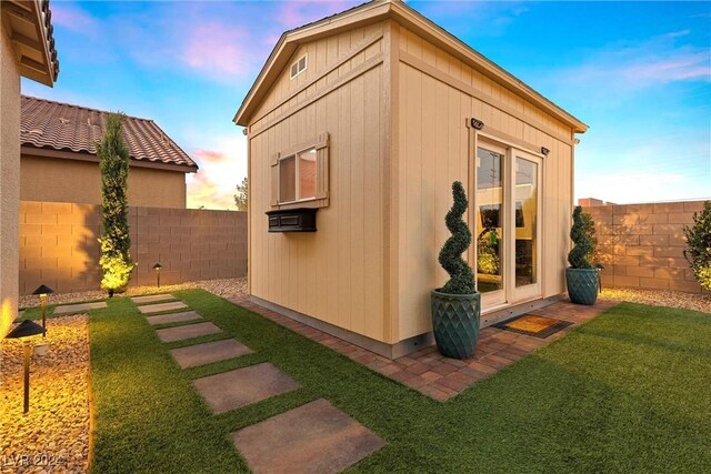 property exterior at dusk featuring french doors and a lawn