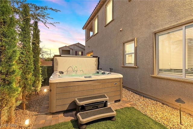 patio terrace at dusk featuring a hot tub