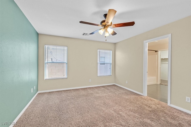 carpeted empty room with ceiling fan and plenty of natural light