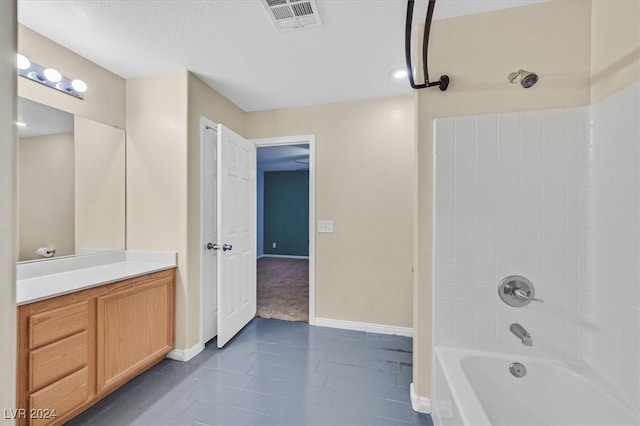 bathroom with tile patterned flooring, vanity, and tiled shower / bath