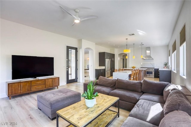 living room featuring light wood-type flooring, ceiling fan, and sink