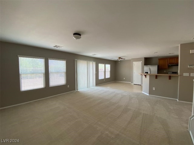 unfurnished living room with light carpet and ceiling fan