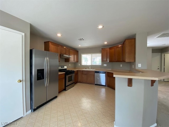 kitchen with appliances with stainless steel finishes, kitchen peninsula, a breakfast bar area, and sink