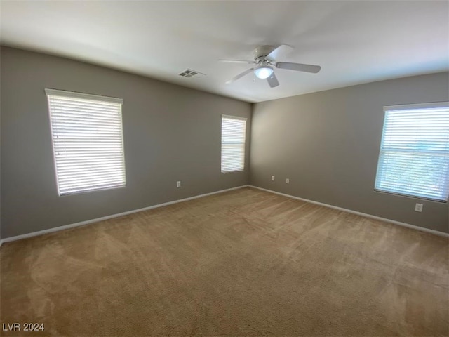 carpeted spare room featuring ceiling fan and a wealth of natural light