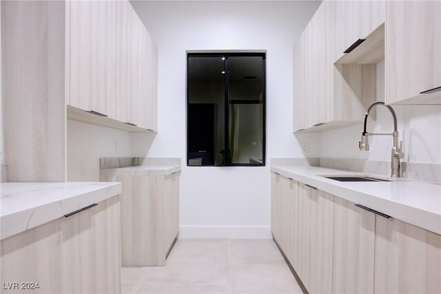 kitchen with light tile patterned floors, light countertops, a sink, modern cabinets, and baseboards