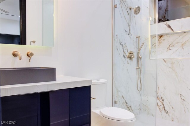 full bath featuring toilet, a marble finish shower, and vanity