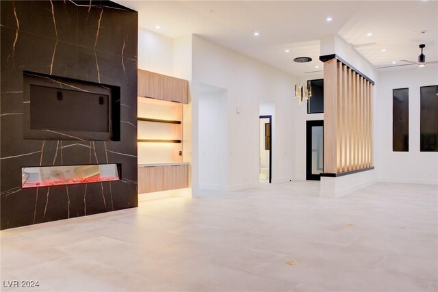 unfurnished living room with a ceiling fan, a towering ceiling, and recessed lighting