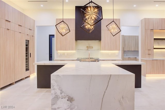 kitchen with hanging light fixtures, an island with sink, modern cabinets, and light brown cabinets