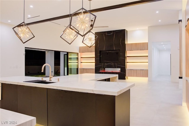 kitchen featuring hanging light fixtures, open floor plan, a sink, light stone countertops, and a chandelier