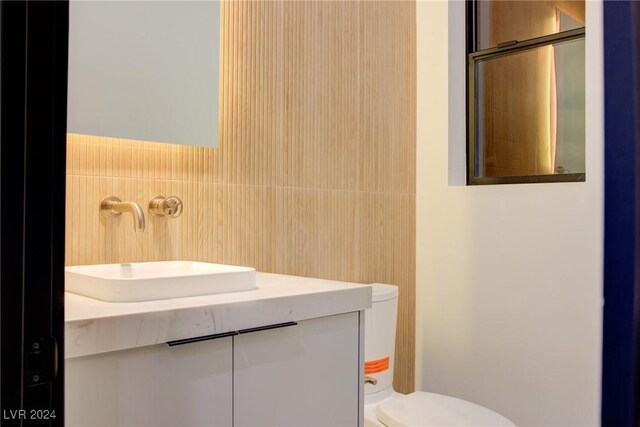 bathroom featuring toilet, a shower with door, vanity, and tile walls