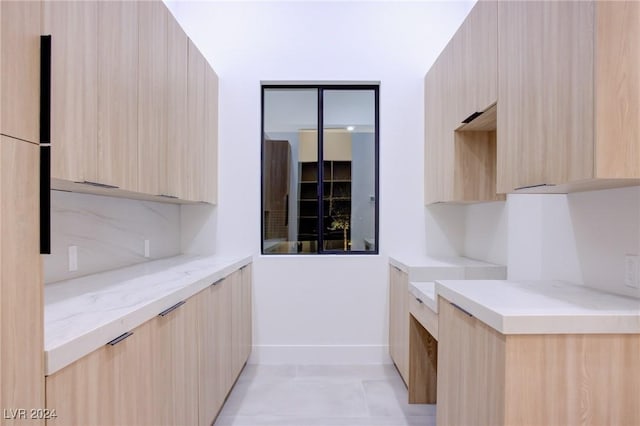 kitchen featuring modern cabinets, decorative backsplash, and light brown cabinetry