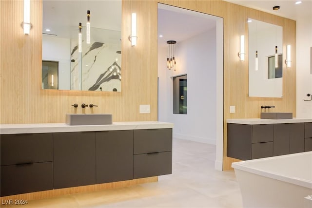 full bathroom with two vanities, a sink, and a freestanding bath