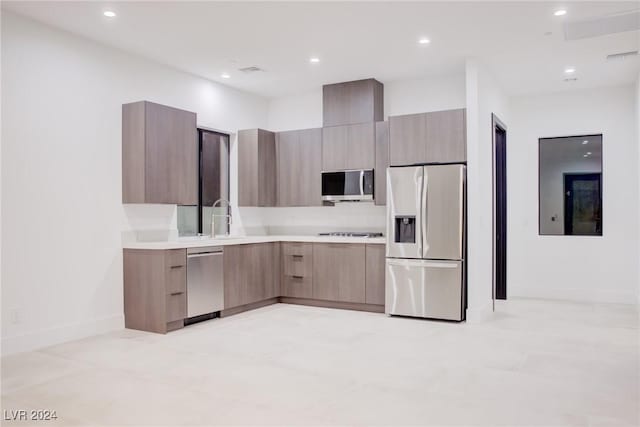 kitchen with light brown cabinets, a sink, light countertops, appliances with stainless steel finishes, and modern cabinets