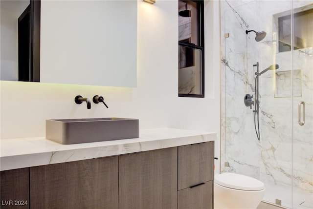 full bathroom with toilet, vanity, and a marble finish shower