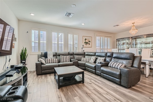 living room featuring a healthy amount of sunlight, light hardwood / wood-style flooring, and a chandelier