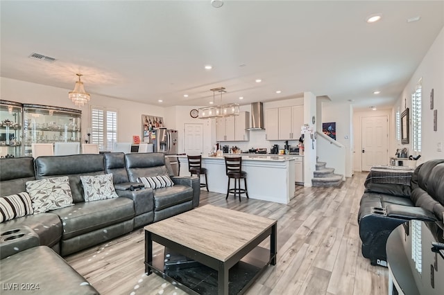 living room with light hardwood / wood-style floors and a notable chandelier