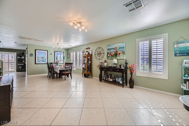 tiled dining room with a notable chandelier and a textured ceiling