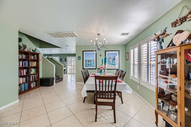 dining space featuring an inviting chandelier, a textured ceiling, and light tile patterned floors