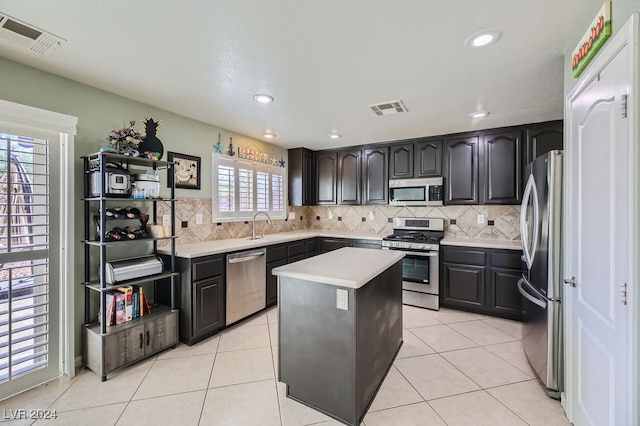 kitchen featuring a healthy amount of sunlight, light tile patterned floors, stainless steel appliances, and a center island