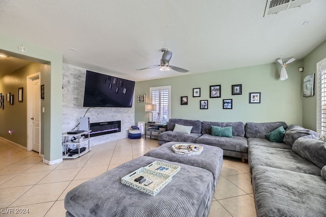 living room featuring ceiling fan, light tile patterned floors, and a fireplace