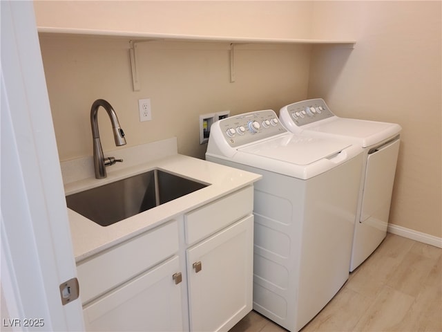 laundry area featuring washing machine and clothes dryer, light wood-type flooring, cabinets, and sink