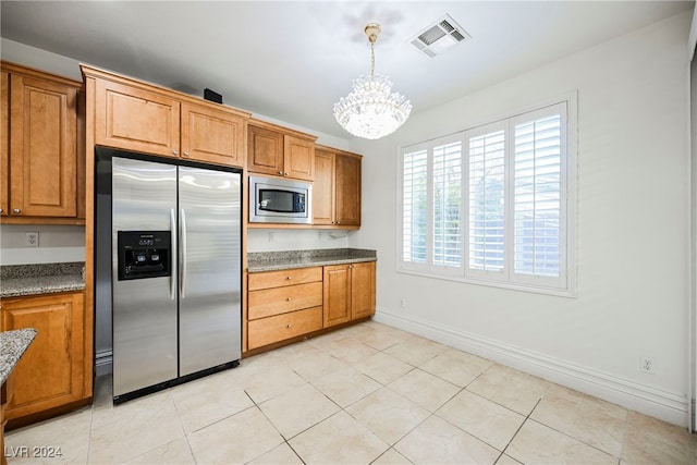 kitchen with light tile patterned flooring, a notable chandelier, stainless steel appliances, and pendant lighting