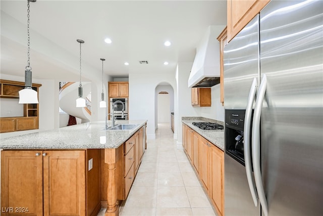 kitchen featuring stainless steel appliances, sink, light stone countertops, pendant lighting, and custom exhaust hood