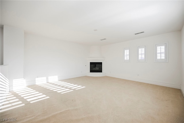 unfurnished living room with light carpet and a large fireplace