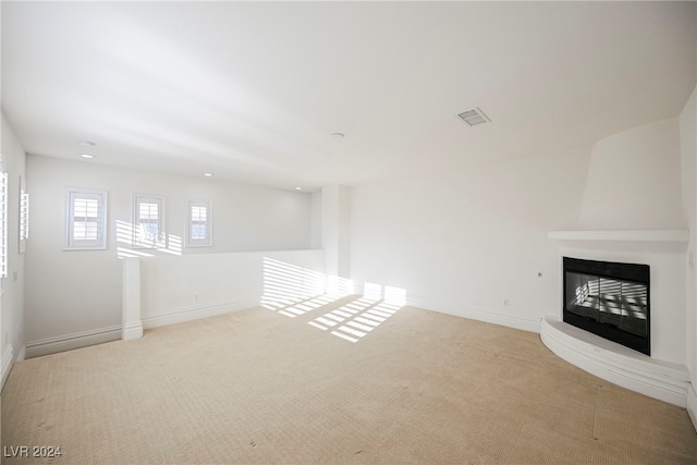 unfurnished living room featuring a large fireplace and light colored carpet