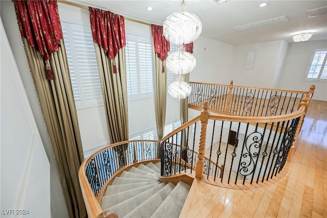 stairs with hardwood / wood-style floors and a chandelier