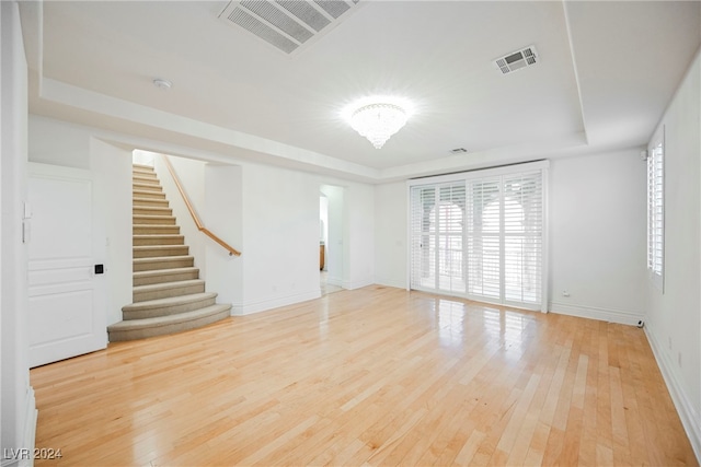 unfurnished room with light hardwood / wood-style flooring and a raised ceiling