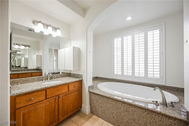 bathroom with vanity, a relaxing tiled tub, plenty of natural light, and tile patterned flooring