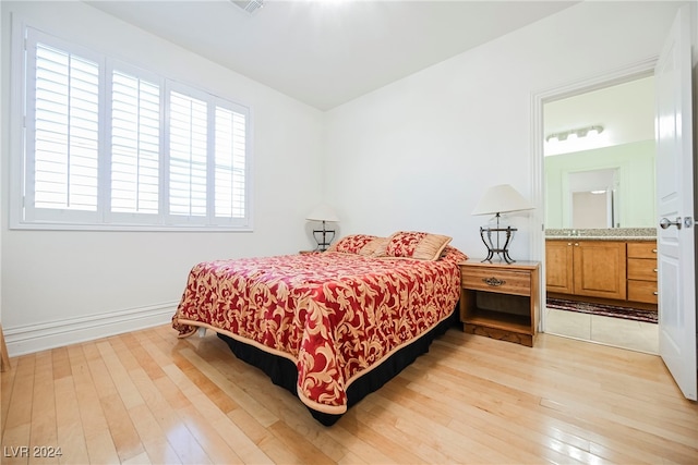 bedroom featuring ensuite bathroom and light hardwood / wood-style flooring