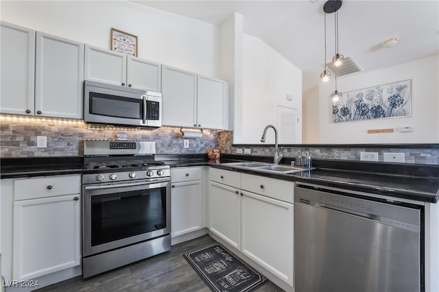 kitchen with appliances with stainless steel finishes, dark wood-type flooring, pendant lighting, white cabinets, and sink